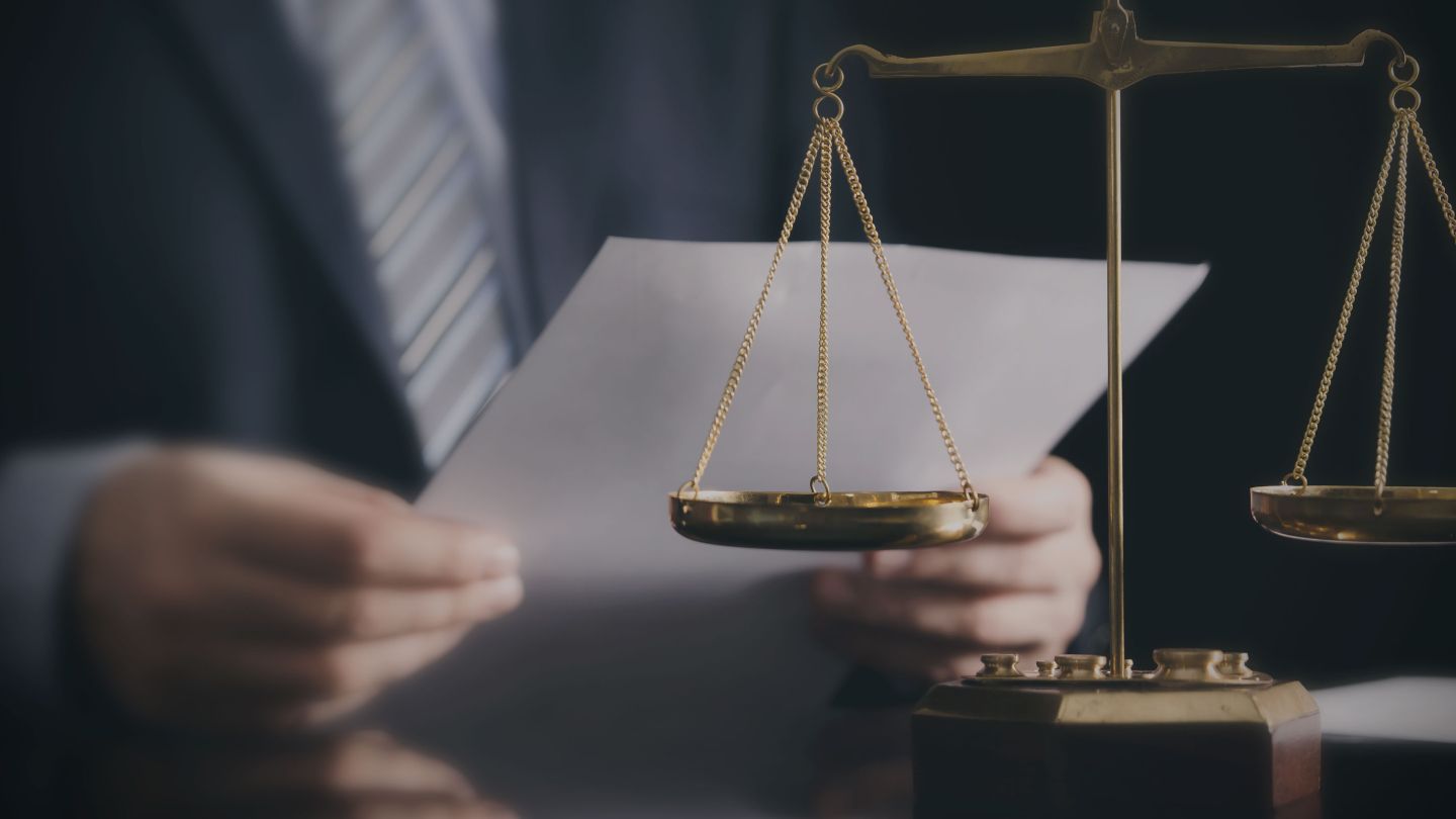 Close up of lawyer working in an office with scales of justice on the desk.
